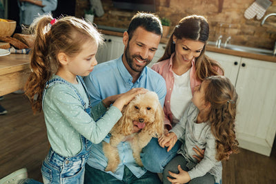 Una familia acaricia a su perro en casa